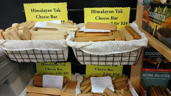 Cheese Bar dog treats in a variety of flavors stacked in baskets on display for sale